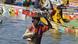 A man emerges from the waters against the backdrop of fishers in canoes with a crate of fish on his head A man emerges from the waters against the backdrop of fishers in canoes with a crate of fish on his head