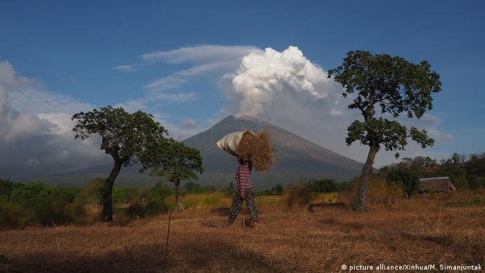 A farmer walks as Mount Agung volcano erupts