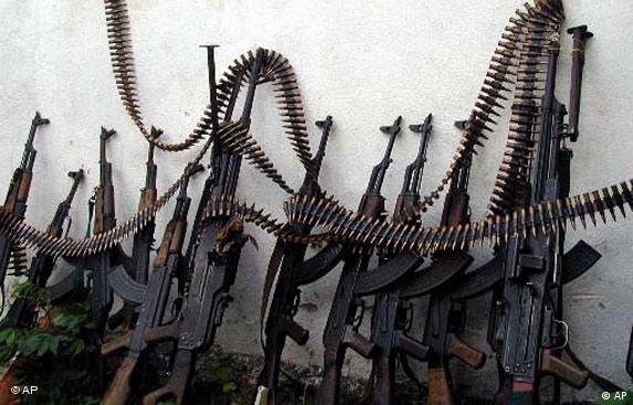 Kalashnikov assault rifles and a couple of heavy machine guns are lines up against a wall at one of Mogadishu four open-air markets, Monday, July 9, 2001. (AP Photo/Osman Hassan)
