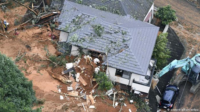 Rescue workers search a house damaged by flooding 