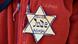 A yellow star with the words "Jude" and "Never Again" A yellow star with the words "Jude" and "Never Again"