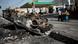 A man pulls a cart as he walks past a burnt car on a street of Port-au-Prince. A man pulls a cart as he walks past a burnt car on a street of Port-au-Prince.
