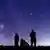 The silhouettes of people as they look up at the stars