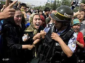 Uighur women grab a police officer as they protest in front of journalists visiting the area in Urumqi, China, Tuesday, July 7, 2009. The city, where rioting and ethnic clashes killed over one hundred people two days ago, remained extremely tense Tuesday, as security officials and police continue to work to restore order. (AP Photo/Ng Han Guan)