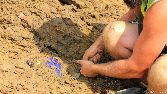An archaeologist extracts a blue water bottle, believed to have belonged to a French soldier. Several bottles and other equipment like toothbrushes were discovered in this location. (DW/M. Hallam)
