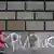Женщина пишет на кирпичной стене слово "кризис"