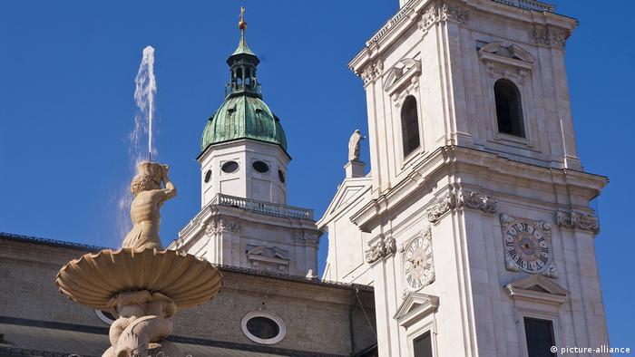 A view of Salzburg Cathedral with church tower and fountain. 