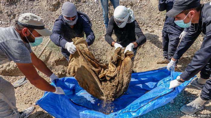 Workers lifting a blanket from a grave (DW/F. Warwick)