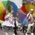 Two gay pride participants dressed as a beauty queen and a sailor and holding rainbow parasols in Munich
