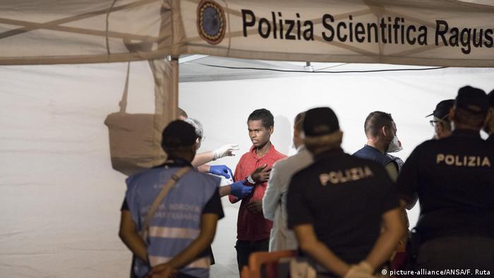 Police check a migrant disembarked from Frontex ship Protector at the port of Pozzallo, Sicily 