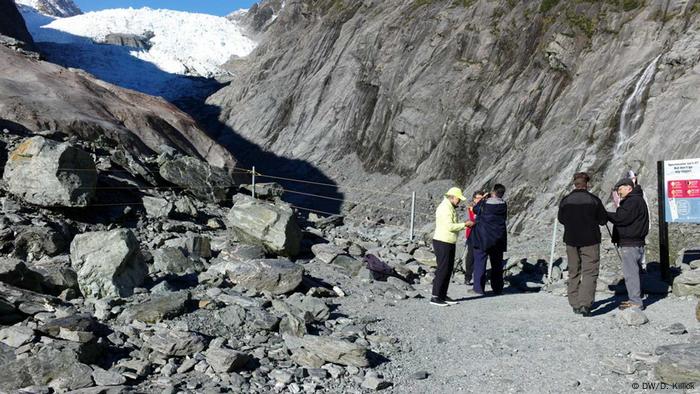 A small group of people stands at the foot of a mountain