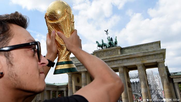 Mesut Özil holds the World Cup trophy in front of the Brandenburg Gate (picture-alliance/GES/M. Gillar)