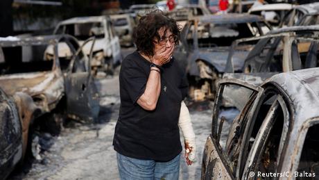 A woman reacts as she tries to find her dog, following a wildfire at the village of Mati