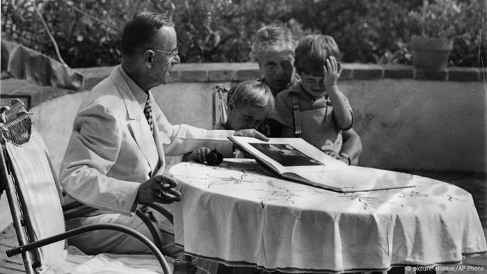 Thomas Mann at the table shows his grandchildren a book