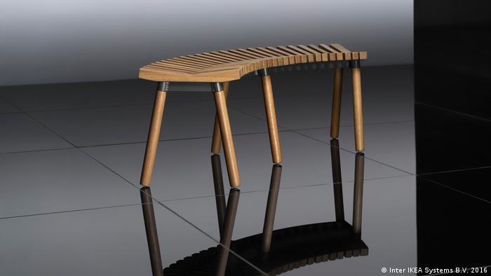 A curbed bench made of wooden slats and supported by six rounded legs. 