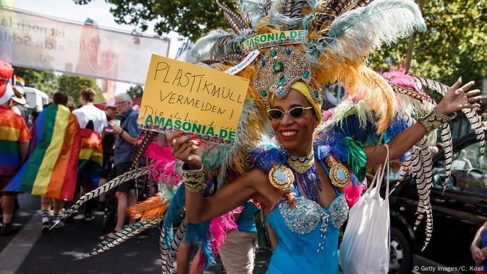 Un fêtard costumé tient une pancarte demandant aux gens d'éviter les déchets plastiques