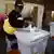 Con bebé a las urnas. Una ciudadana deposita su voto en Harare, capital de Zimbabue.