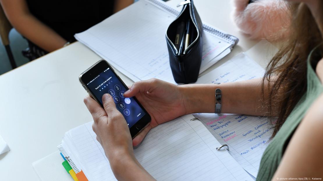 Jovem acessa um smartphone em sala de aula