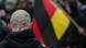 A German right-wing extremist at a rally, with a German flag in the background A German right-wing extremist at a rally, with a German flag in the background