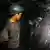 Miners dig in a dark coal mine