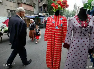 Uighur people walk past women's clothing on a street at Uighur sector in Urumqi, western China's Xinjiang province, Tuesday, July 14, 2009. The capital of China's western Xinjiang region was tense amid tight security Tuesday, a day after police fatally shot two Uighur men and wounded a third, more than a week after deadly ethnic rioting. (AP Photo/Eugene Hoshiko)