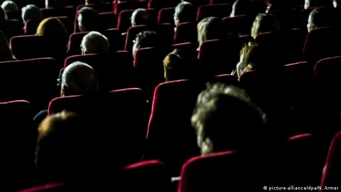 The backs of heads of people sitting in a cinema
