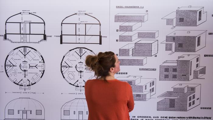 Eine Frau steht vor dem Rundhaus-Modell von Carl Fieger und dem Baukastensystem von Walter Gropius.