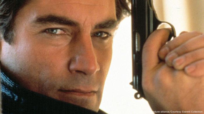 Timothy Dalton posiert mit gezückter Waffe für die Kamera. 