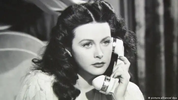 Actress and inventor Hedy Lamarr speaking on an old-fashioned phone in a black-and-white photo.
