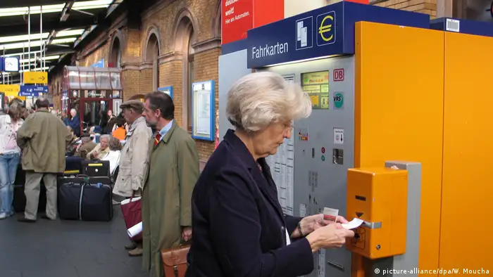 Mujer comprando un billete en una estacon de trenes.
