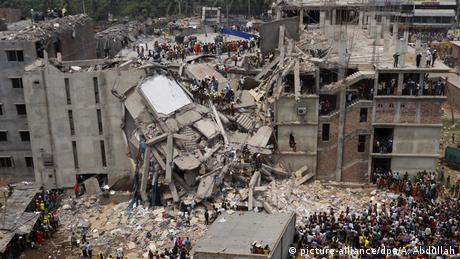 People crowd around the destroyed Rana Plaza building