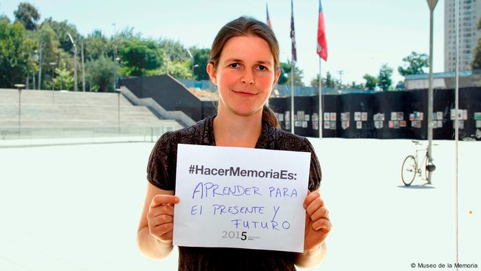 Mujer en el exterior del museo con papel que dice #HacerMemoriaEs: “Aprender para el presente y el futuro”
