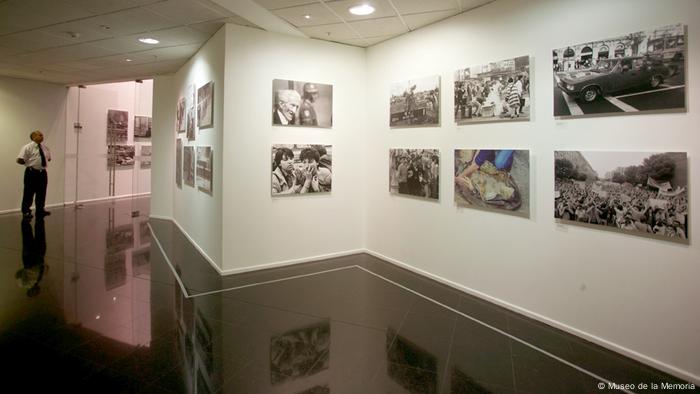 Sala de exposición fotográfica, con una persona al lado izquierdo. 