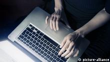 Frau mit einem Laptop-Computer zu Hause, Draufsicht, Facebook-Login-Seite auf dem Display | Verwendung weltweit, Keine Weitergabe an Wiederverkäufer.