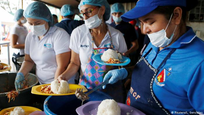 Women dish out food into plates in a refugee center (Reuters/L. Gonzales)