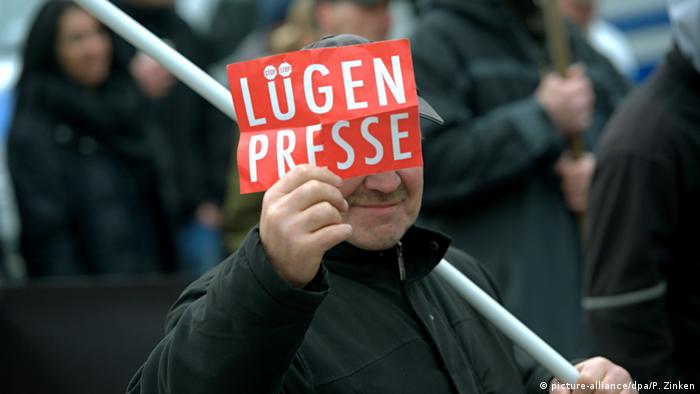 A man hold a placard that reads lying press