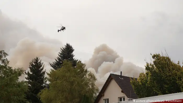 Ein Hubschrauber fliegt über dem Rauch am Horizont von Frohnsdorf (Foto: picture-alliance)