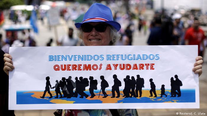 Foto de una mujer de Costa Rica con un rótulo que dice bienvenidos refugiados