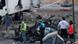 Helfer vor zerstörtem Auto (Foto: AP) Helfer vor zerstörtem Auto (Foto: AP)