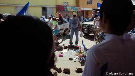 Exposición fotográfica Miradas en Resistencia. Ciudadno nicaragüense observa el croquis policial de una persona fallecida en el pavimento, en La Pedrada (Álvaro Cantillano).