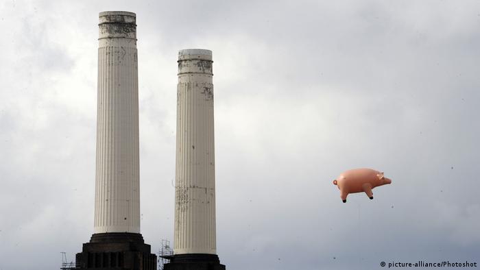 Ein aufgeblasenes rosa Schwein fliegt neben zwei Fabrikschloten (picture-alliance/Photoshot)