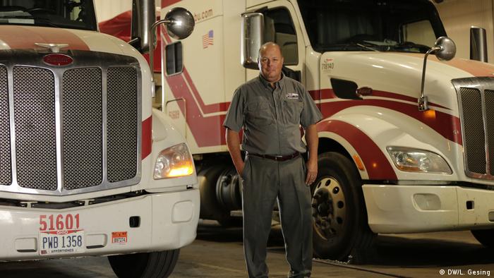 A man standing in front of two trucks