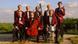Ein 8-köpfiges Musikerensemble in rotem Frack und dunklen Hosen, mit Insturmenten posierend vor grüner Landschaft(Copyright: Kurverwaltung Juist) Ein 8-köpfiges Musikerensemble in rotem Frack und dunklen Hosen, mit Insturmenten posierend vor grüner Landschaft(Copyright: Kurverwaltung Juist)