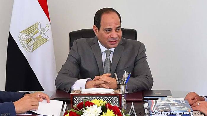 Egyptian President Abdel-Fattah el-Sissi clasping his hands whilst seated at a desk
