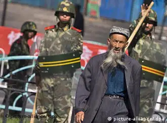 An ethnic Uighur man passes by security forces standing guard outside the Grand Bazaar in Urumqi, Xinjiang province, China, 16 July 2009. The presence of security forces in Urumqi is still very obvious although a number of troops seem to have been left the streets. Tension can still be felt in some areas of the city but businesses are slowly coming back to life, and residents are trying to go back to their routine. EPA/DIEGO AZUBEL +++(c) dpa - Report+++