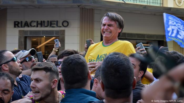 Jair Bolsonaro, rodeado de gente y con gesto de dolor. 