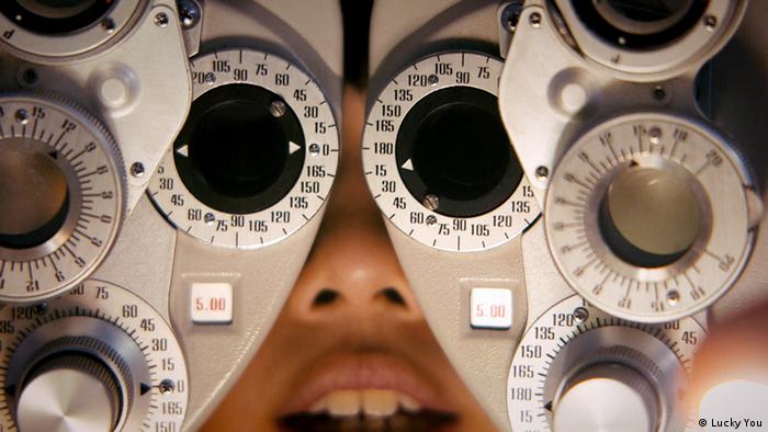 Eine Patientin schaut in einen Apparat beim Augenarzt