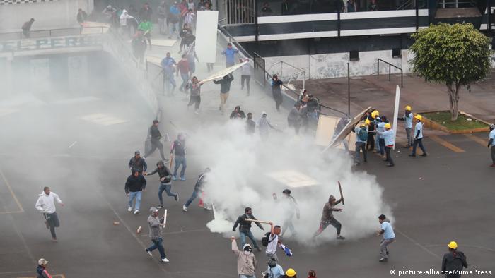 Police, soccer fans and religious group members clash in front of a stadium as tear gas is deployed