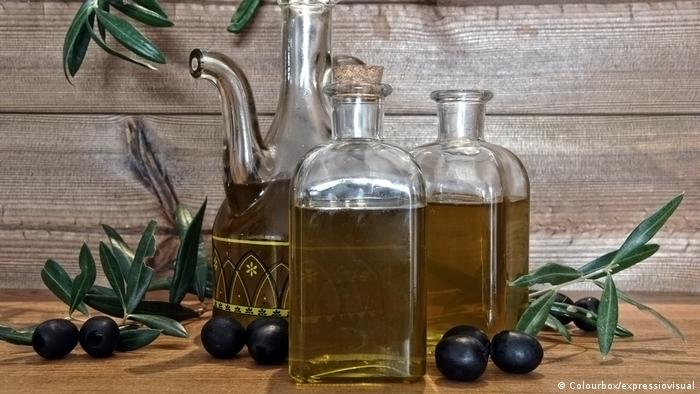 Olivenzweige und Olivenöl in Glasflaschen auf einem Tisch