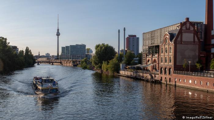 A boat on the river Spree running through the heart of Berlin. The tall TV tower is visible in the background